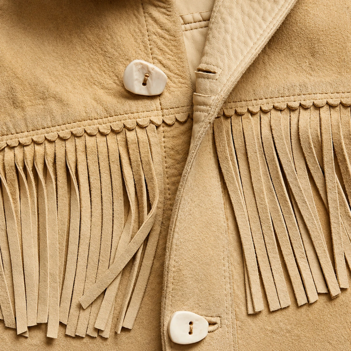Close-up of brown suede leather jacket showing fringe and button details